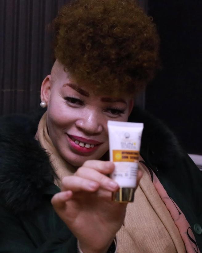 A woman holding up a tube of sunscreen.