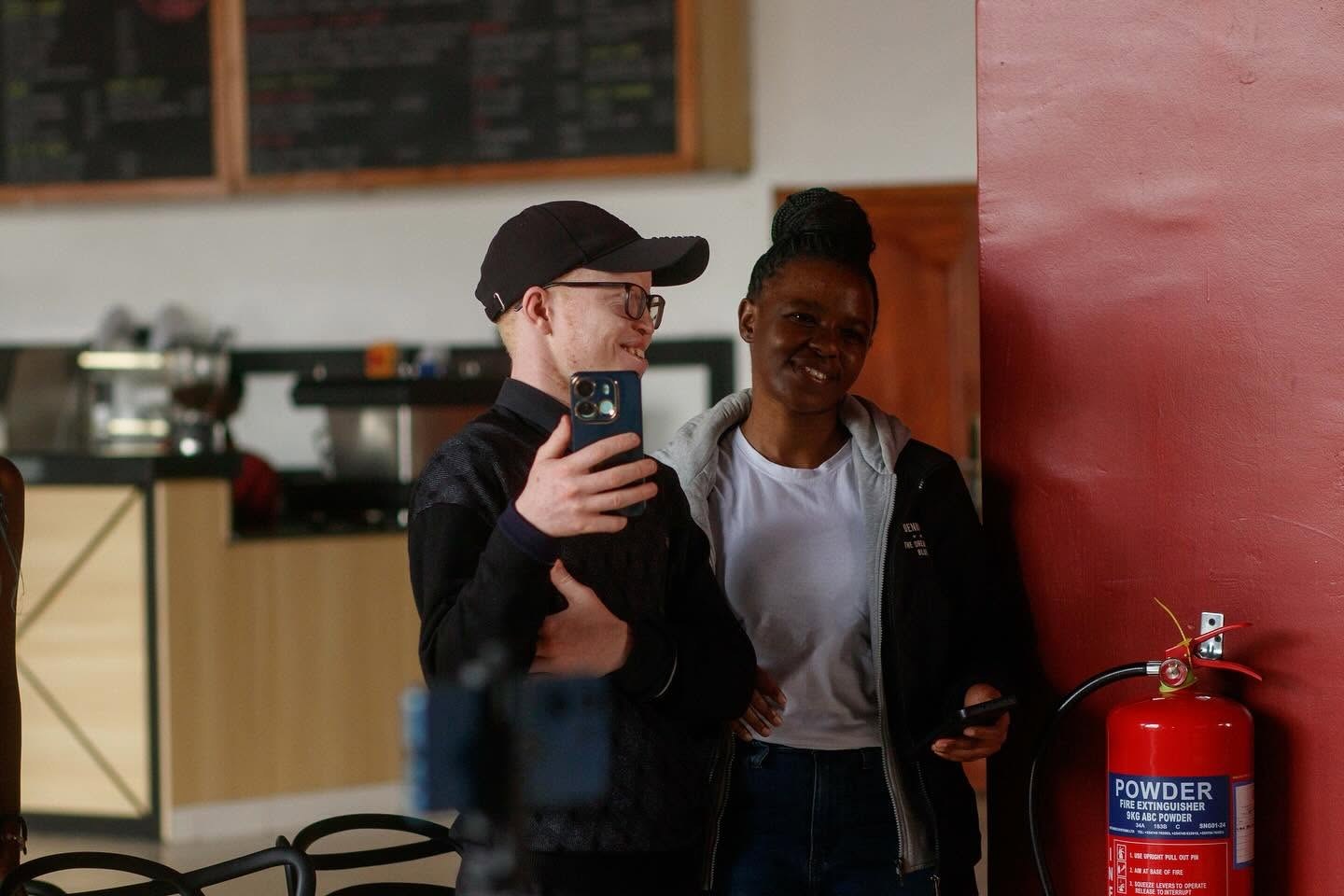 Two people filming on a phone at a Black Albinism event.