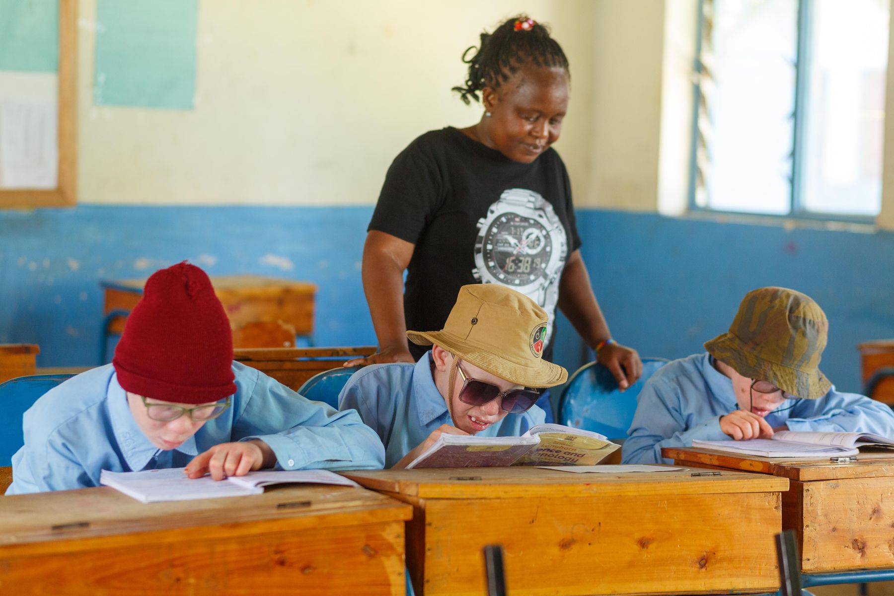 A learner with albinism reading large print in class.